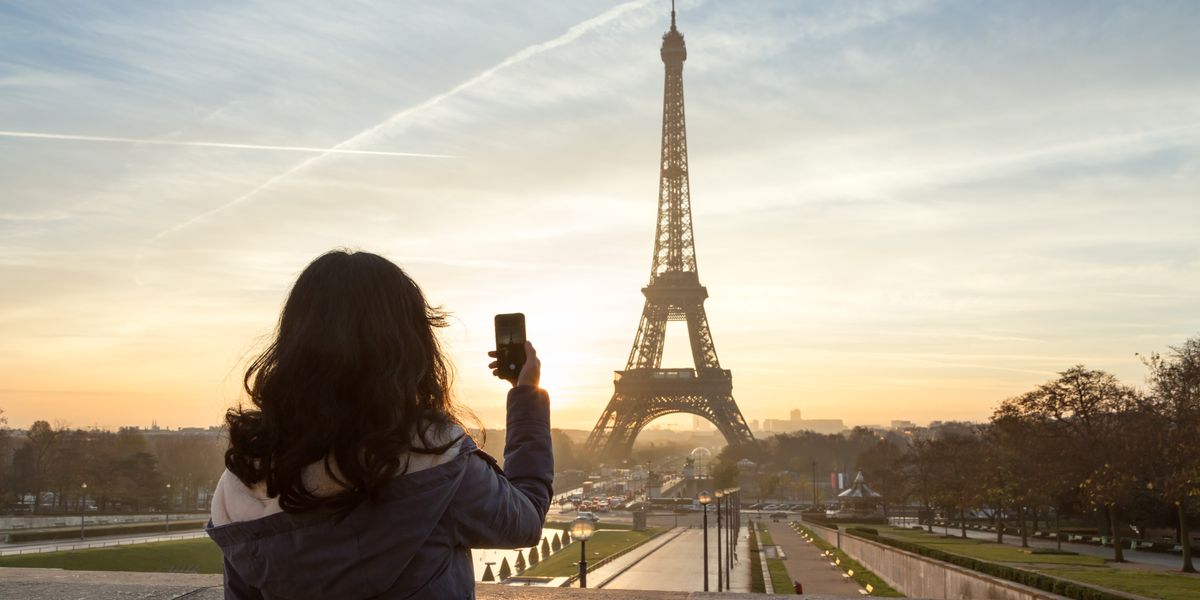egy turista nő Párizsban az Eiffel-tornyot fotózza