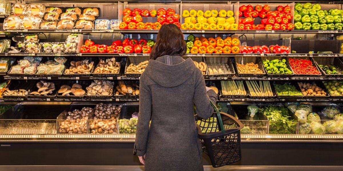 egy vásárló áll a zöldségek előtt egy boltban