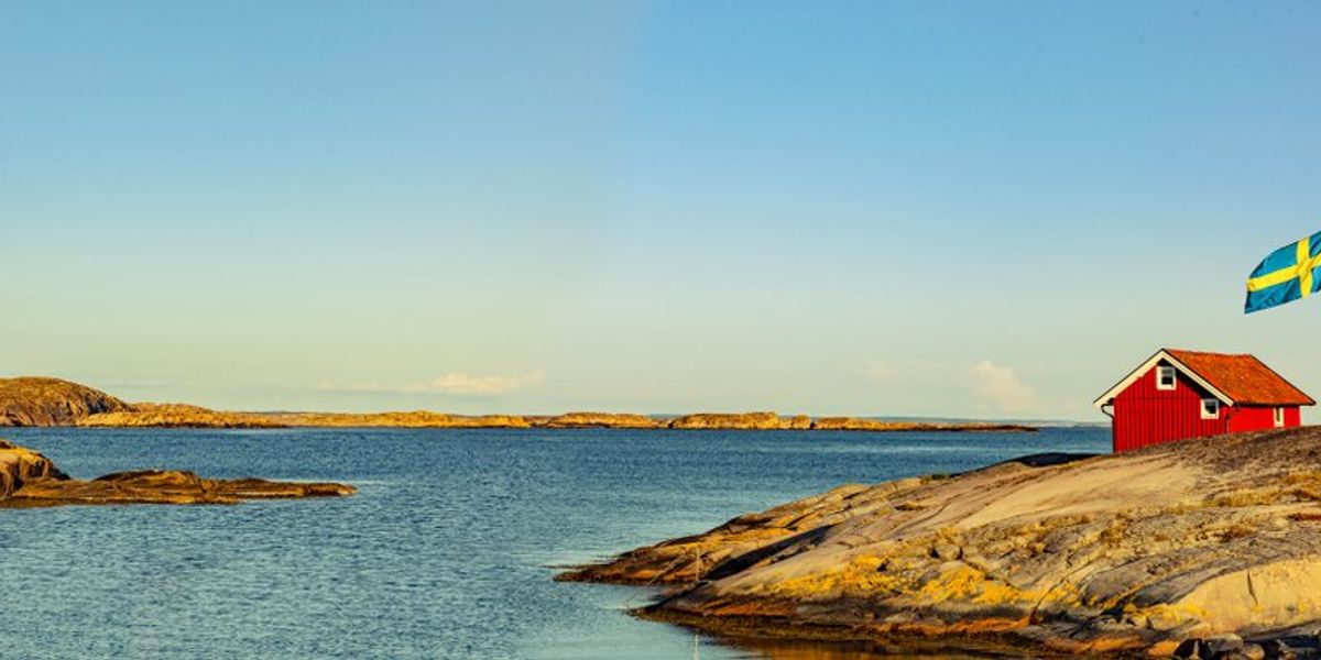 egy vörös faház és a svéd zászló a tengerparton