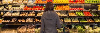 egy vásárló áll a zöldségek előtt egy boltban