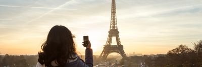egy turista nő Párizsban az Eiffel-tornyot fotózza