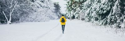 egy sárga kabátos férfi sétál a hóban