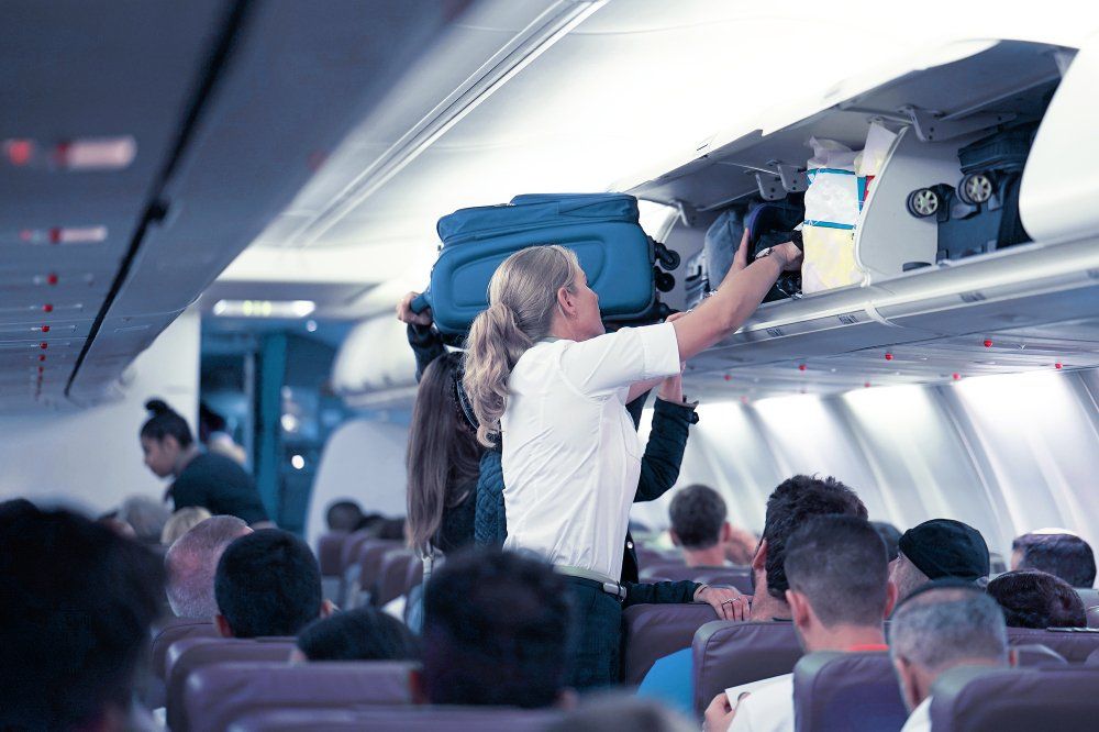 A légiutas-kísérő segít az utasoknak elhelyezni csomagjaikat a repülőgép utasterében
