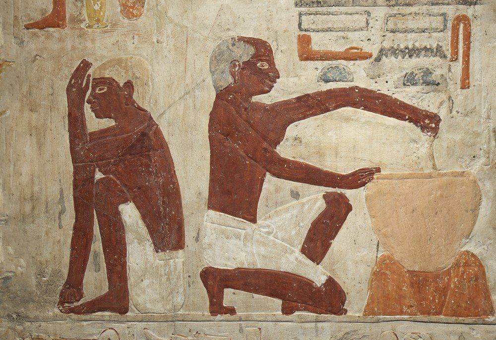 Falfestmény egy ókori egyiptomi emberről, aki kenyérkészítéshez szükséges tésztát készít (I. e. 2500-2350)