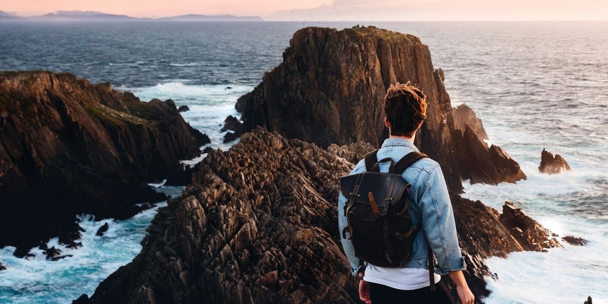 Malin-félsziget, az Ír-sziget legészakibb pontja, férfi áll a sziklák és a tenger előtt